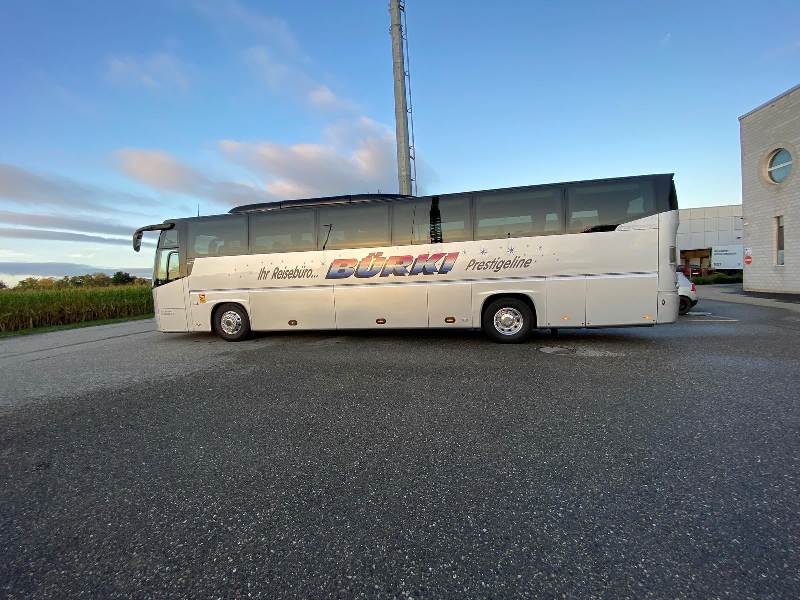 Reisebus mit der Aufschrift Ihr Reisebüro BÜRKLI Prestige auf einem Parkplatz bei sonnigem Wetter.