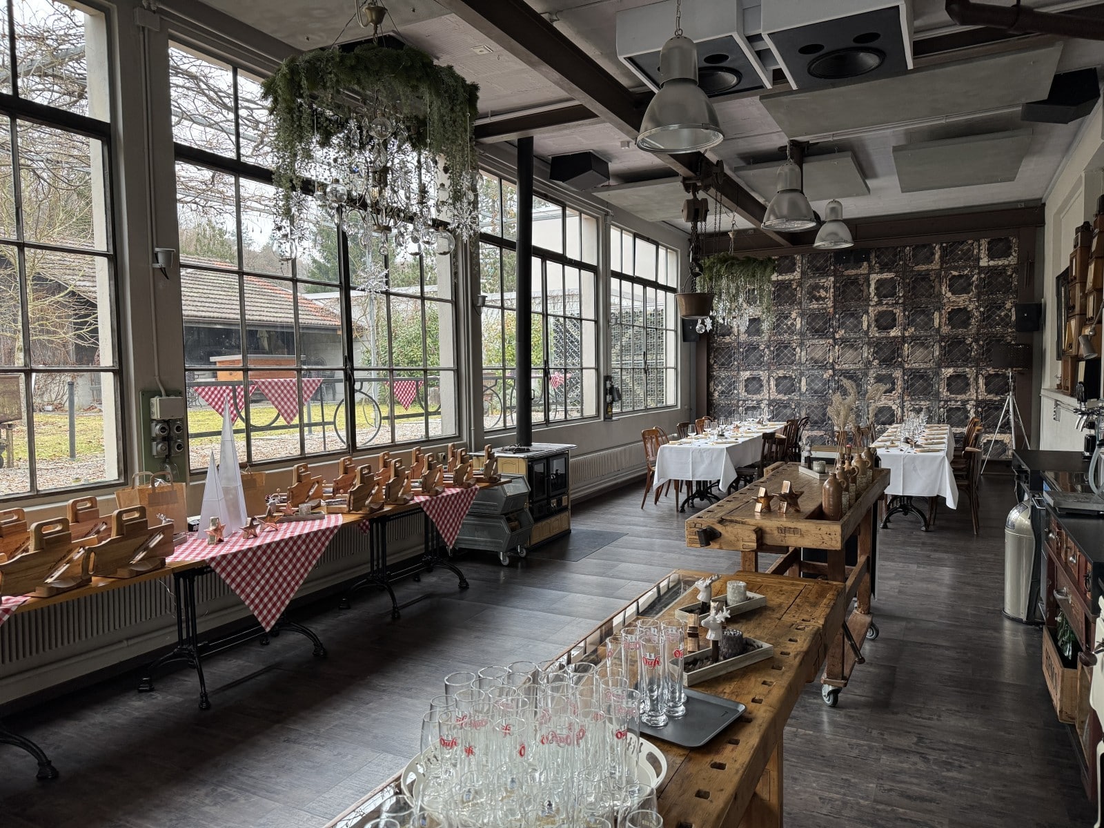 Gemütlicher, rustikaler Veranstaltungsraum mit gedeckten Tischen und großen Fenstern für Feste und Events.